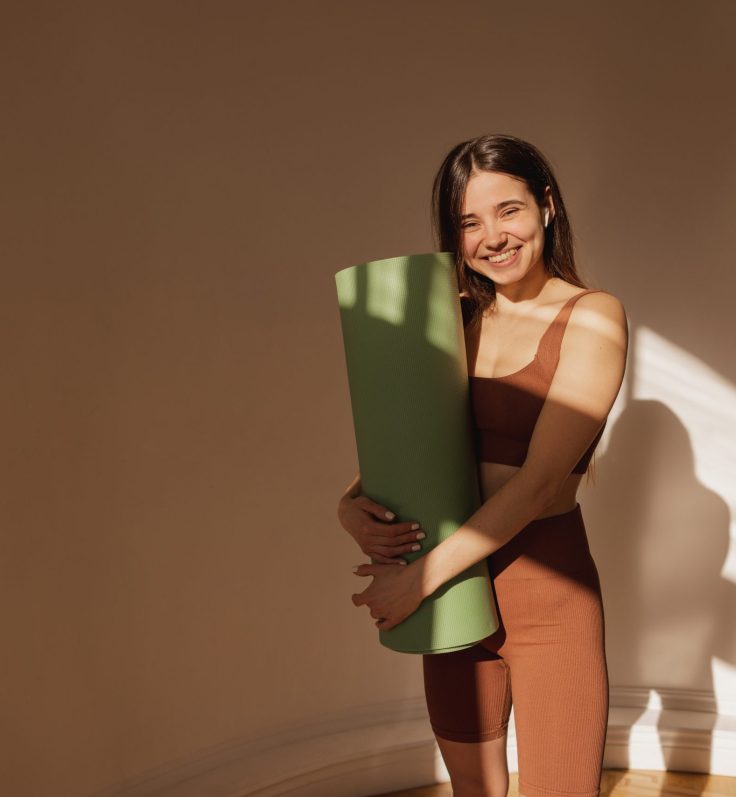 athletic-happy-young-caucasian-woman-holding-yoga-mat-after-fitness-class-smiling-brunette-woman-wears-top-leggings-lifestyle-sport-concept